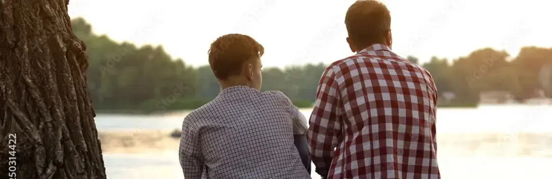 Father and teenage son sitting together